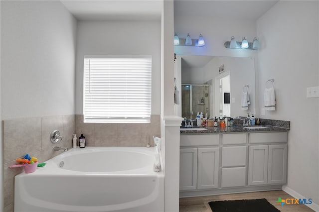 bathroom featuring vanity, hardwood / wood-style flooring, and plus walk in shower