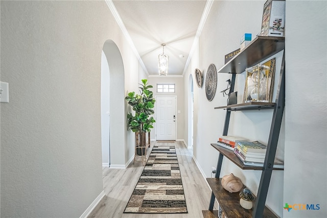 corridor with light hardwood / wood-style floors, crown molding, and vaulted ceiling