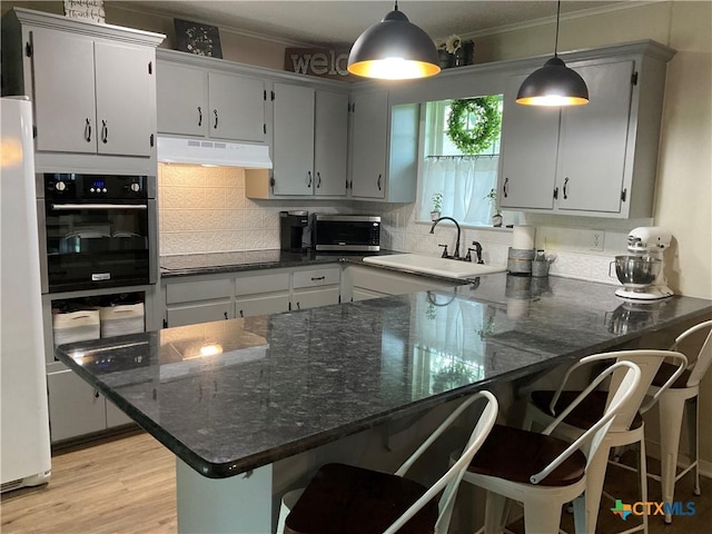 208 Old Fort Gates Rd, Gatesville, TX 76528 - kitchen featuring black appliances, under cabinet range hood, a sink, a peninsula, and tasteful backsplash