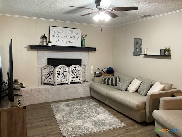 208 Old Fort Gates Rd, Gatesville, TX 76528 - living room featuring ceiling fan, wood finished floors, a fireplace, ornamental molding, and a textured ceiling