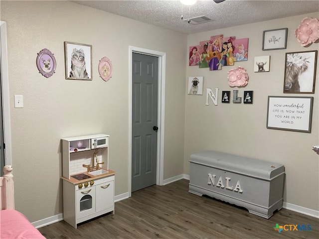 208 Old Fort Gates Rd, Gatesville, TX 76528 - playroom featuring dark wood-style floors, a ceiling fan, baseboards, and a textured ceiling