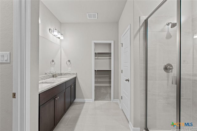 bathroom featuring vanity, a shower with shower door, and tile patterned floors