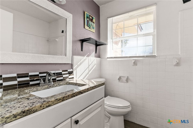 full bath featuring toilet, tile walls, wainscoting, and vanity