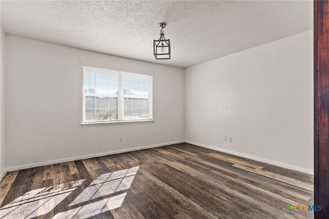 empty room featuring baseboards, a textured ceiling, and wood finished floors