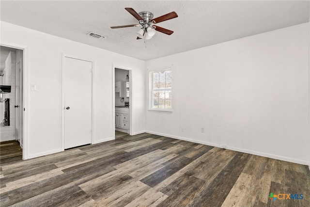 unfurnished bedroom featuring visible vents, a textured ceiling, wood finished floors, and ensuite bathroom