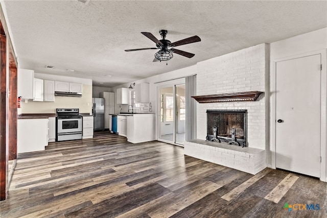 kitchen featuring ceiling fan, dark wood-type flooring, appliances with stainless steel finishes, dark countertops, and open floor plan