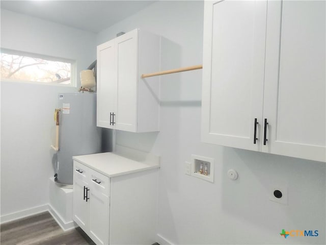 laundry area featuring water heater, electric dryer hookup, cabinets, dark hardwood / wood-style floors, and washer hookup