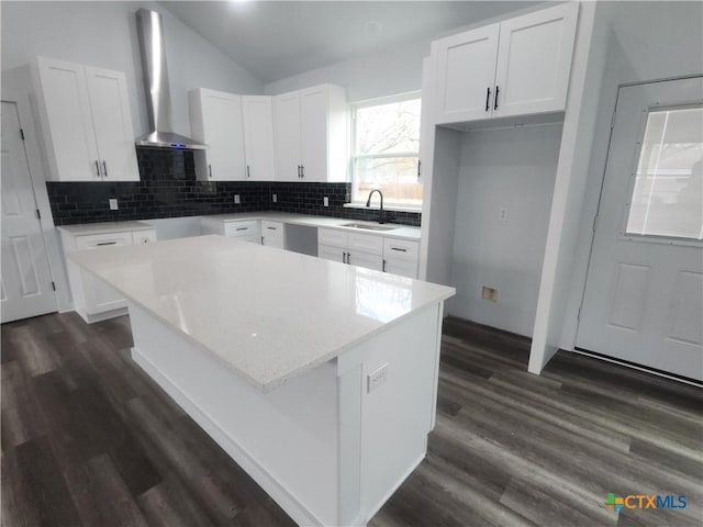 kitchen featuring sink, white cabinetry, backsplash, a center island, and wall chimney exhaust hood