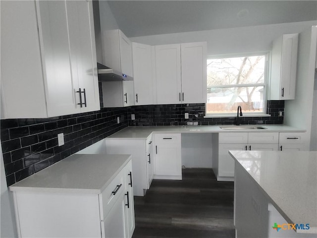 kitchen featuring dark hardwood / wood-style floors, sink, white cabinets, backsplash, and light stone counters