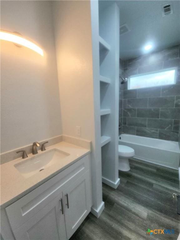 full bathroom featuring tiled shower / bath, hardwood / wood-style floors, vanity, toilet, and built in shelves