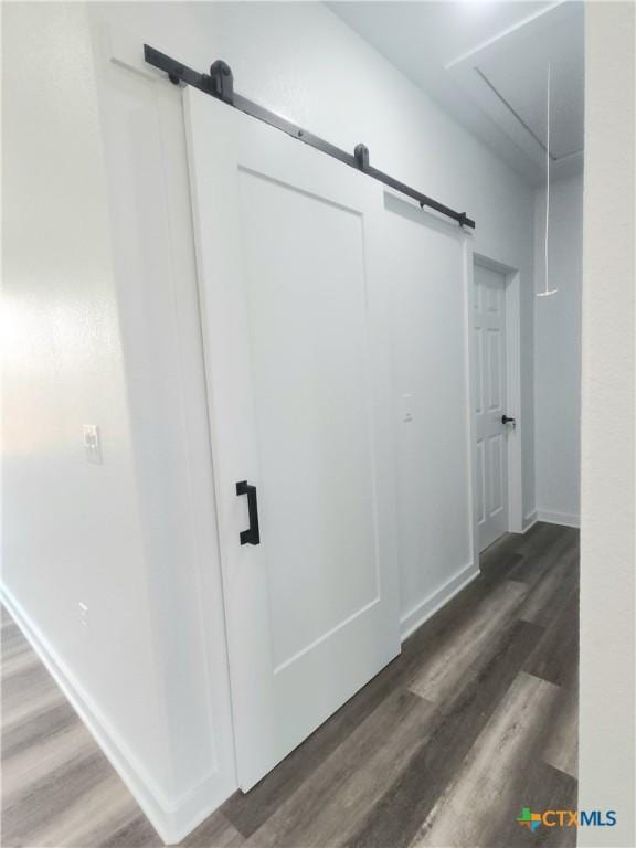 corridor featuring dark wood-type flooring and a barn door