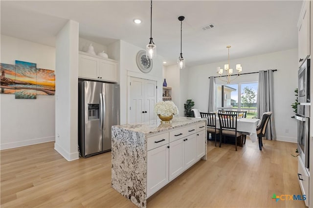 kitchen with white cabinets, light stone counters, stainless steel appliances, light wood-style floors, and a chandelier