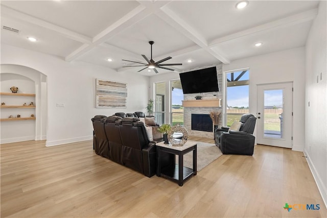 living room with light wood-type flooring, a stone fireplace, visible vents, and coffered ceiling