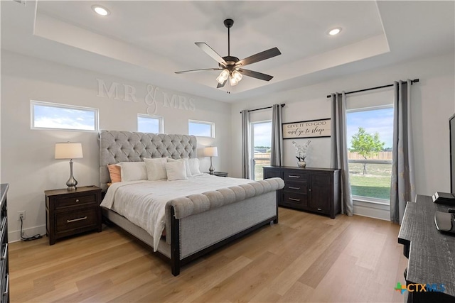bedroom featuring light wood-type flooring, a tray ceiling, and recessed lighting