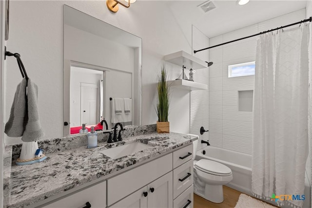 full bathroom with visible vents, toilet, vanity, and shower / tub combo