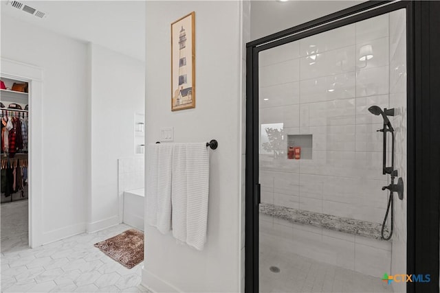 bathroom with a shower stall, visible vents, a walk in closet, a bath, and baseboards
