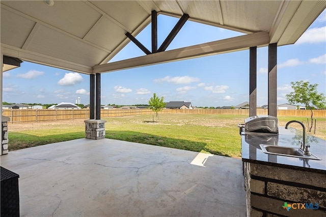 view of patio / terrace with a fenced backyard, a sink, and a grill