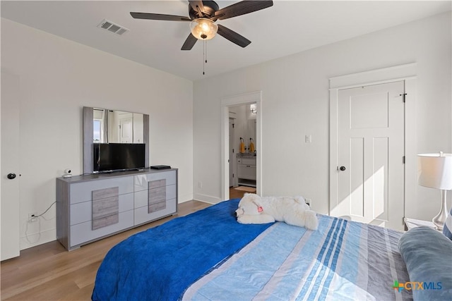 bedroom featuring light wood-type flooring, visible vents, a ceiling fan, and ensuite bathroom