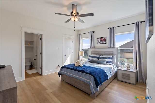 bedroom with ceiling fan, light wood-style flooring, baseboards, and ensuite bathroom
