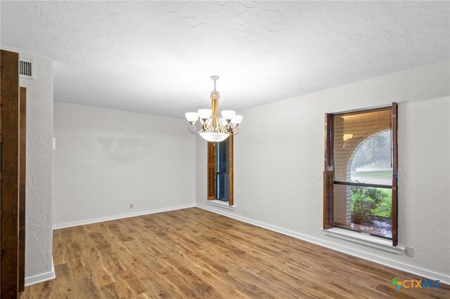 213 Tracy Ln, Victoria, TX 77904 - empty room with a chandelier, wood finished floors, and a textured ceiling