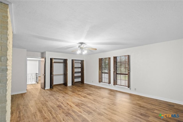 213 Tracy Ln, Victoria, TX 77904 - unfurnished bedroom with wood finished floors, a textured ceiling, multiple closets, and ceiling fan