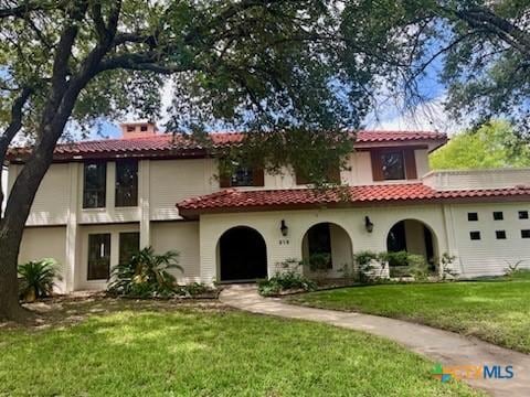 213 Tracy Ln, Victoria, TX 77904 - mediterranean / spanish house with a front yard, stucco siding, a chimney, and a tile roof