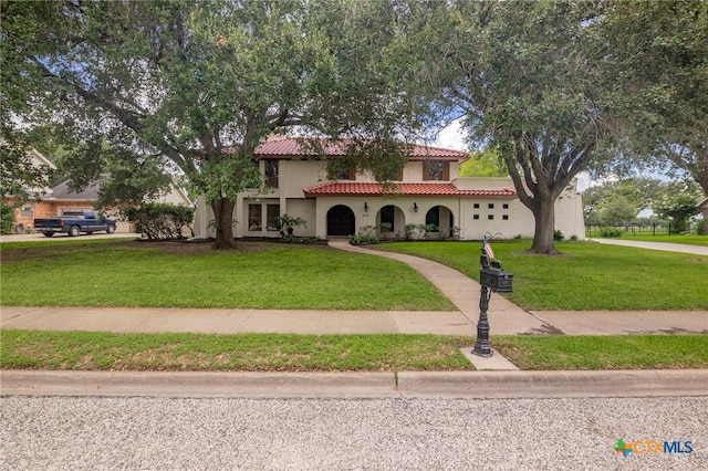 213 Tracy Ln, Victoria, TX 77904 - mediterranean / spanish house featuring a tiled roof, a front yard, an attached garage, and stucco siding