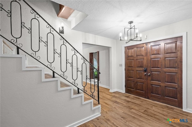 213 Tracy Ln, Victoria, TX 77904 - foyer entrance featuring wood finished floors, stairs, a chandelier, and a textured ceiling
