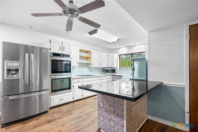 213 Tracy Ln, Victoria, TX 77904 - kitchen featuring stainless steel appliances, white cabinetry, light wood-style flooring, a peninsula, and decorative backsplash