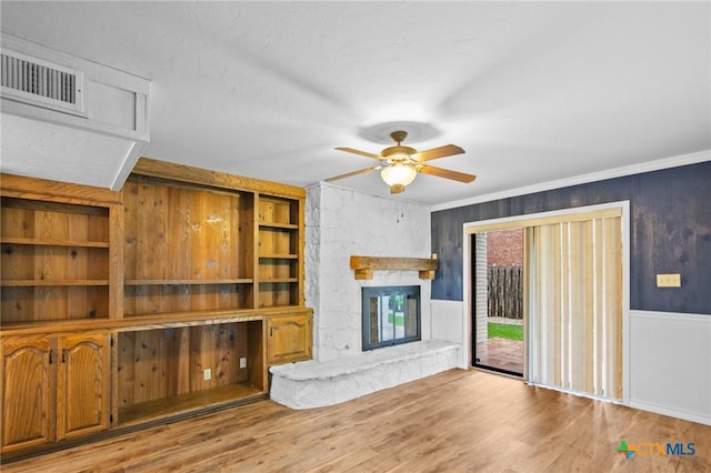 213 Tracy Ln, Victoria, TX 77904 - unfurnished living room featuring a ceiling fan, a fireplace, wood finished floors, wood walls, and crown molding