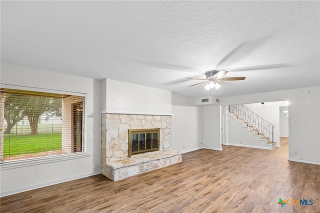213 Tracy Ln, Victoria, TX 77904 - unfurnished living room with wood finished floors, ceiling fan, a stone fireplace, and stairway