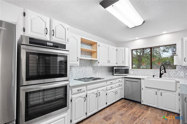 213 Tracy Ln, Victoria, TX 77904 - kitchen featuring appliances with stainless steel finishes, light countertops, decorative backsplash, wood finished floors, and a textured ceiling