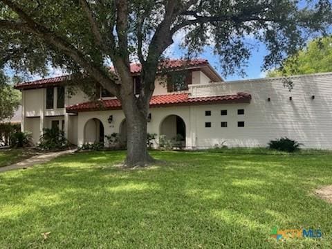 213 Tracy Ln, Victoria, TX 77904 - mediterranean / spanish house featuring a front yard, a tiled roof, and stucco siding