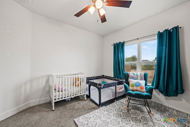 bedroom featuring carpet, ceiling fan, and a crib