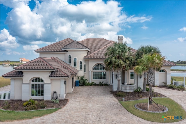 mediterranean / spanish-style house featuring a front lawn and a water view