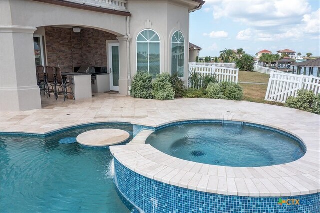 153 E Tuscany Way, Port Oconnor, TX 77979 - view of pool with an outdoor kitchen, fence, a patio, a pool with connected hot tub, and a grill