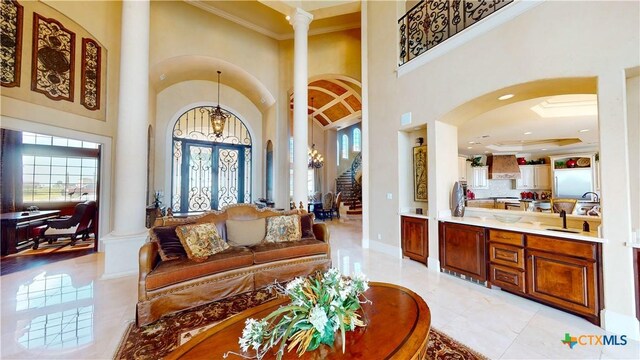 153 E Tuscany Way, Port Oconnor, TX 77979 - living area featuring arched walkways, decorative columns, a high ceiling, stairs, and crown molding