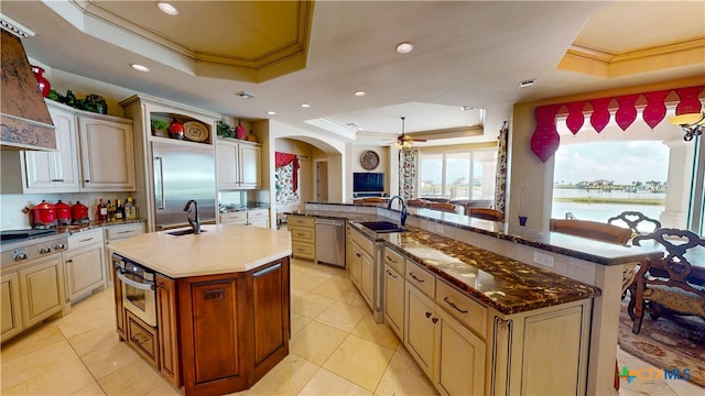 kitchen featuring sink, a raised ceiling, and an island with sink