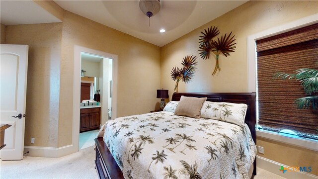 bedroom with light colored carpet, ceiling fan, and connected bathroom