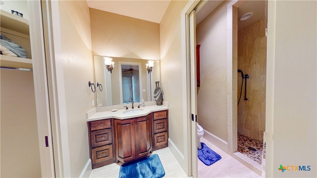 bathroom featuring vanity, tile patterned flooring, toilet, and a tile shower