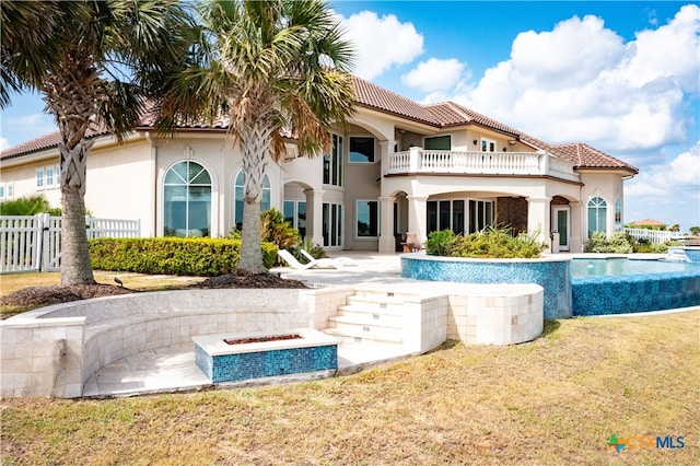 rear view of property with a pool with hot tub, a patio area, a lawn, and a balcony