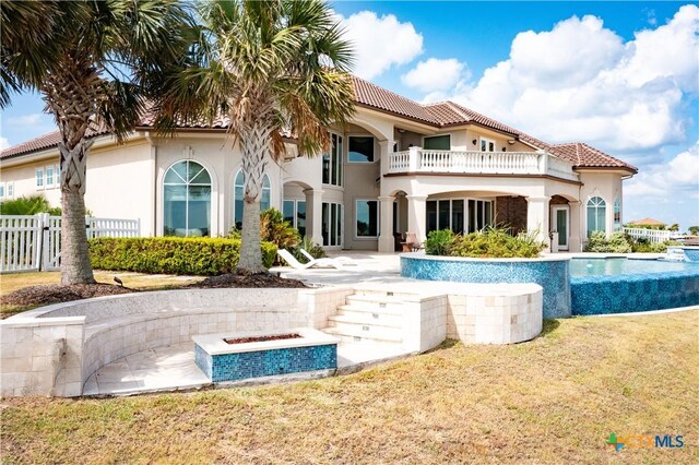 153 E Tuscany Way, Port Oconnor, TX 77979 - rear view of property with a balcony, an outdoor fire pit, a patio area, and a tiled roof