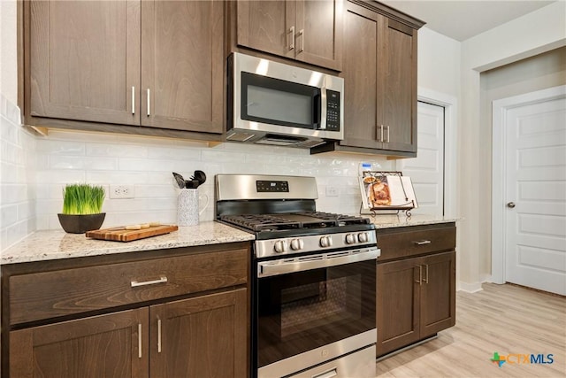 2917 Sage Ranch Dr, Leander, TX 78641 - kitchen featuring appliances with stainless steel finishes, dark brown cabinetry, and light stone counters