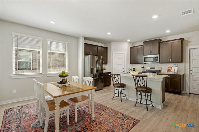 2917 Sage Ranch Dr, Leander, TX 78641 - kitchen featuring stainless steel appliances, dark brown cabinets, light wood-style flooring, backsplash, and recessed lighting