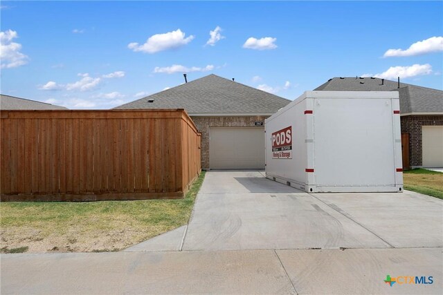2917 Sage Ranch Dr, Leander, TX 78641 - view of side of property featuring driveway, a shingled roof, brick siding, and a garage