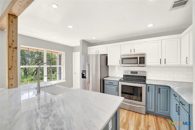 661 Abels Way, Canyon Lake, TX 78133 - kitchen with appliances with stainless steel finishes, white cabinets, a sink, decorative backsplash, and light wood-style floors