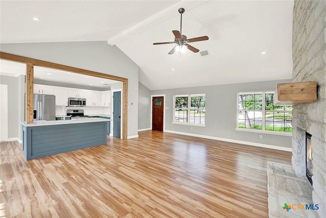 661 Abels Way, Canyon Lake, TX 78133 - unfurnished living room featuring light wood finished floors, a fireplace, a ceiling fan, baseboards, and beamed ceiling