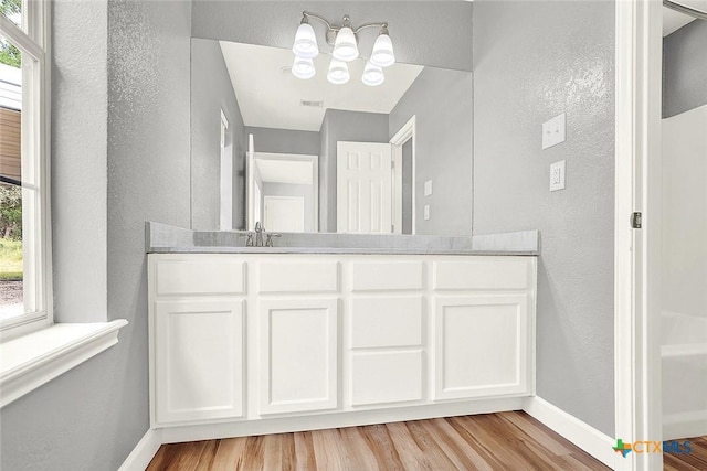 661 Abels Way, Canyon Lake, TX 78133 - bathroom with plenty of natural light, wood finished floors, a textured wall, and a chandelier