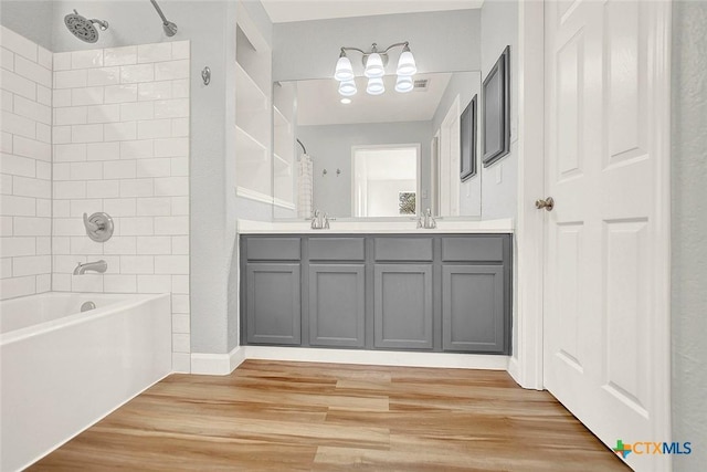 661 Abels Way, Canyon Lake, TX 78133 - full bathroom featuring wood finished floors, washtub / shower combination, double vanity, and a chandelier