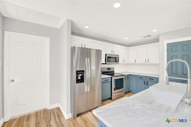 661 Abels Way, Canyon Lake, TX 78133 - kitchen featuring appliances with stainless steel finishes, white cabinets, baseboards, backsplash, and light wood finished floors